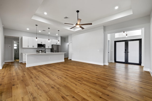 kitchen featuring open floor plan, a tray ceiling, appliances with stainless steel finishes, and white cabinetry