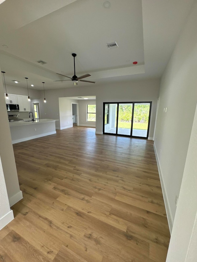 unfurnished living room with light hardwood / wood-style floors, ceiling fan, and sink