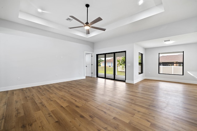 empty room featuring visible vents, a tray ceiling, and baseboards