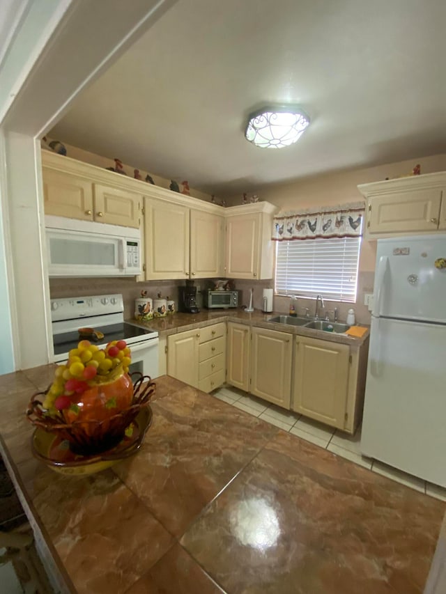 kitchen featuring light tile patterned floors, white appliances, sink, and cream cabinetry