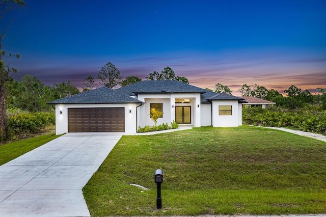 view of front of house featuring roof with shingles, a yard, stucco siding, concrete driveway, and a garage