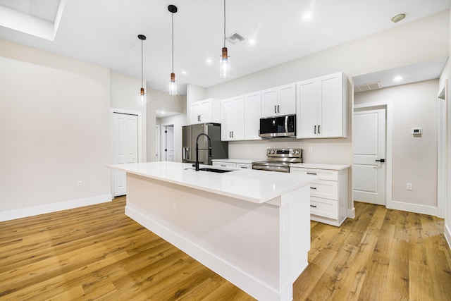 kitchen with a sink, light countertops, appliances with stainless steel finishes, an island with sink, and pendant lighting