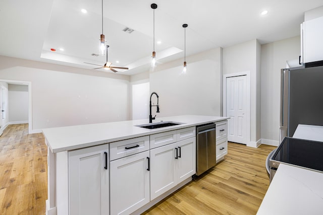 kitchen featuring a raised ceiling, appliances with stainless steel finishes, sink, and white cabinets