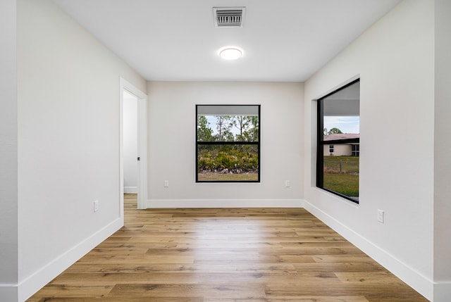 empty room featuring light wood-type flooring, visible vents, and baseboards