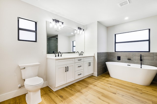 full bathroom with hardwood / wood-style flooring, vanity, plus walk in shower, and toilet