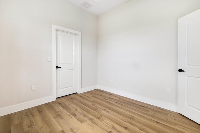 empty room featuring light wood-style flooring, visible vents, and baseboards