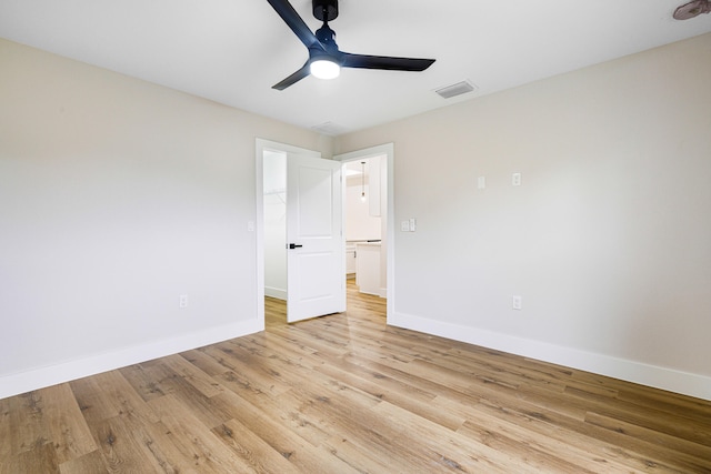 unfurnished bedroom with visible vents, baseboards, a ceiling fan, light wood-style flooring, and a walk in closet