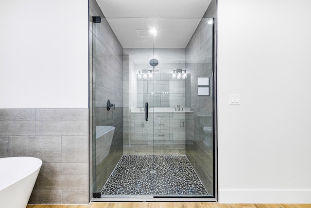 full bathroom with a soaking tub, a shower stall, and tile walls