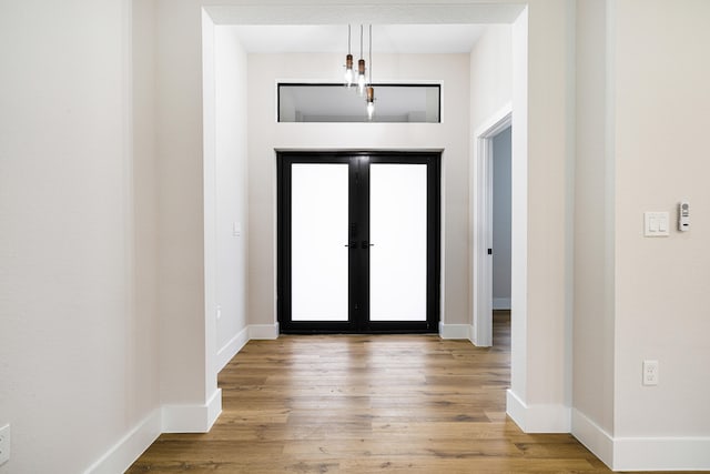 foyer featuring light wood-style floors, baseboards, and french doors