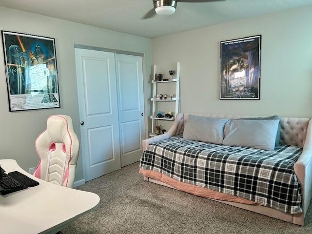 carpeted bedroom featuring ceiling fan and a closet