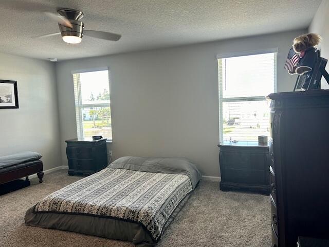 carpeted bedroom with a textured ceiling and ceiling fan