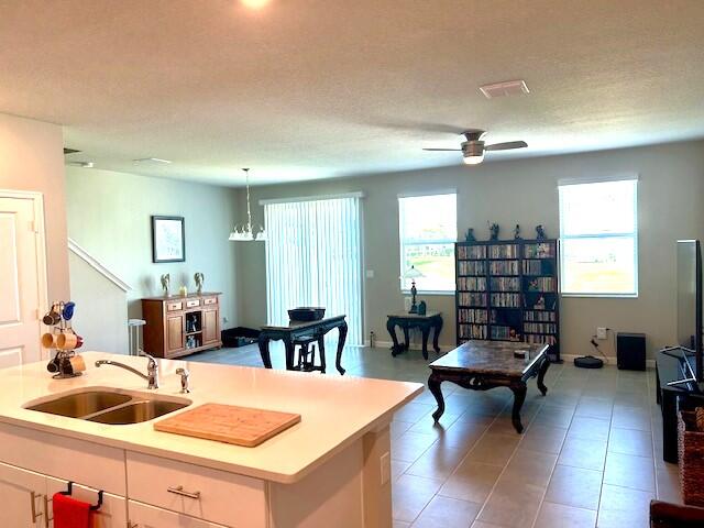 kitchen with decorative light fixtures, ceiling fan with notable chandelier, a textured ceiling, and sink