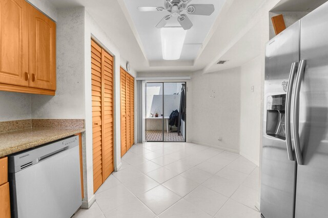 kitchen featuring appliances with stainless steel finishes, a raised ceiling, light tile patterned floors, and ceiling fan