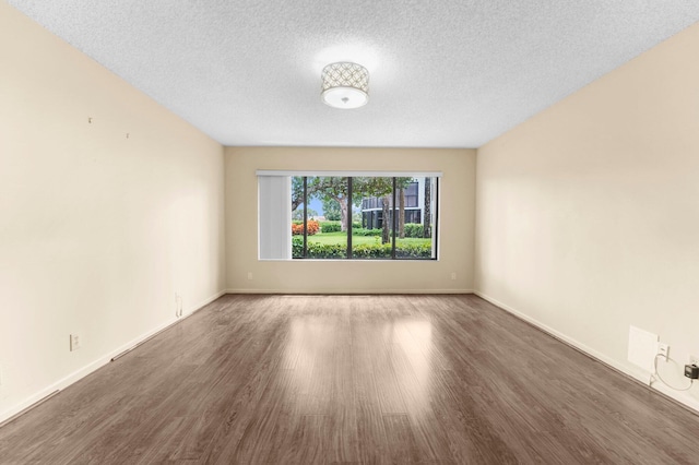 unfurnished room featuring dark wood-type flooring and a textured ceiling