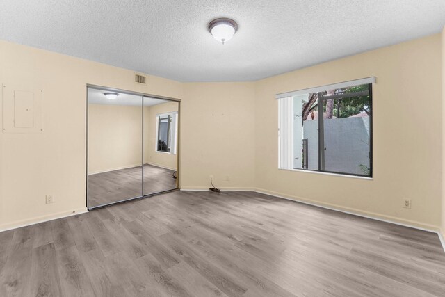 unfurnished bedroom featuring a closet, a textured ceiling, and light hardwood / wood-style flooring