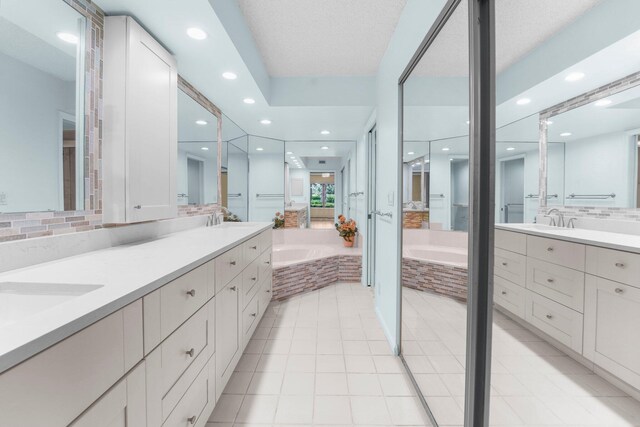 bathroom featuring vanity, a textured ceiling, tile patterned flooring, and tiled bath