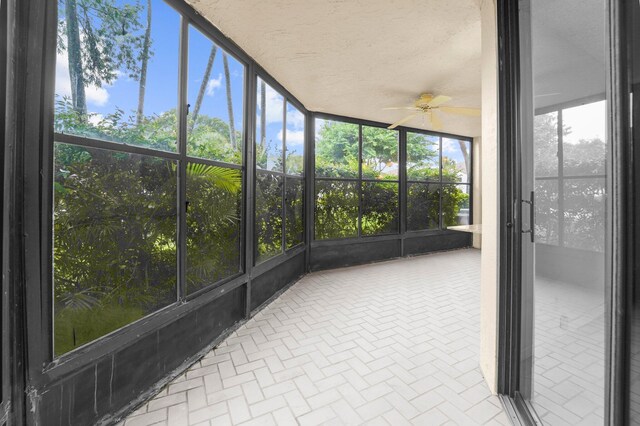 unfurnished sunroom featuring ceiling fan and a wealth of natural light