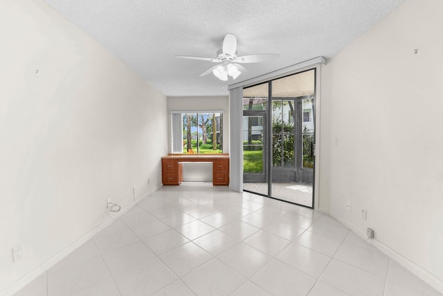 empty room with a textured ceiling, light tile patterned flooring, and ceiling fan