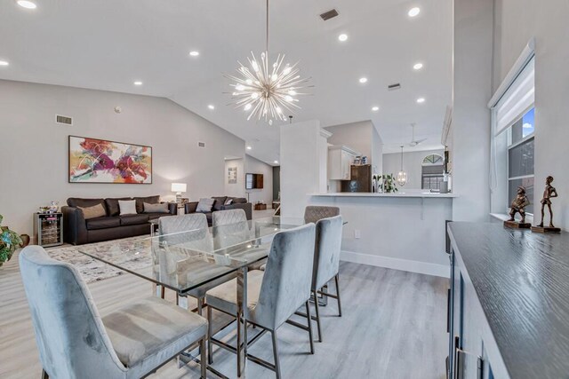 dining area with high vaulted ceiling, a wealth of natural light, light hardwood / wood-style flooring, and an inviting chandelier