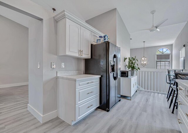 kitchen featuring white cabinetry, black appliances, light stone counters, ceiling fan, and light hardwood / wood-style floors