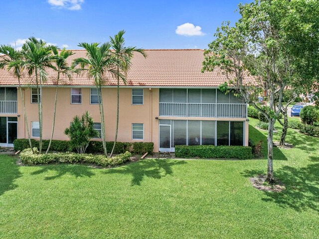 rear view of house featuring a yard and a sunroom