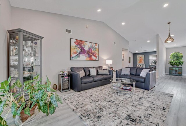 living room with light wood-type flooring and high vaulted ceiling