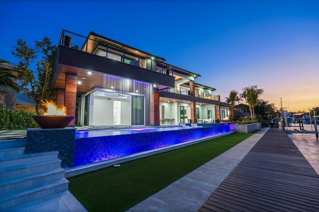 rear view of house with a balcony and an infinity pool