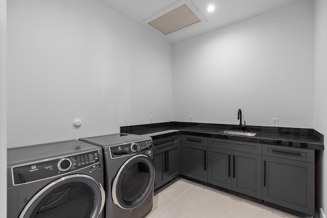 clothes washing area with washing machine and clothes dryer, cabinets, and sink