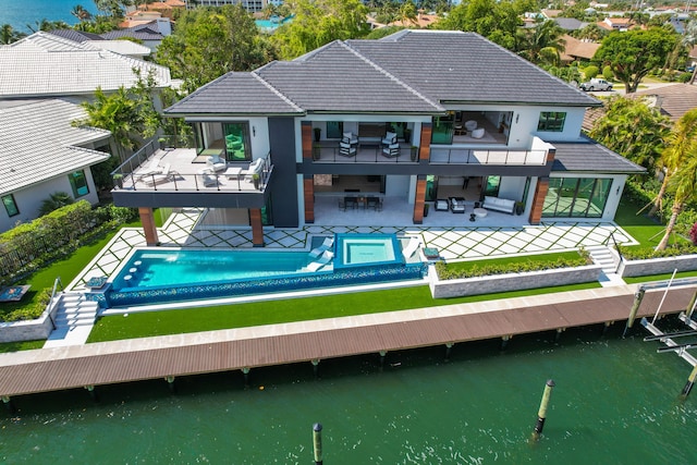 rear view of property featuring an outdoor bar, a water view, and a patio area