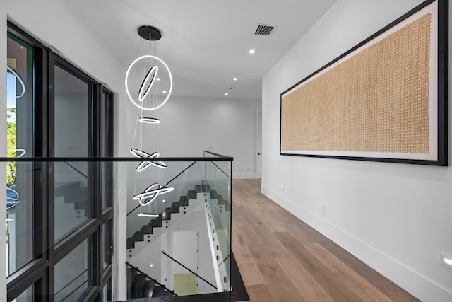 hallway with hardwood / wood-style floors and an inviting chandelier