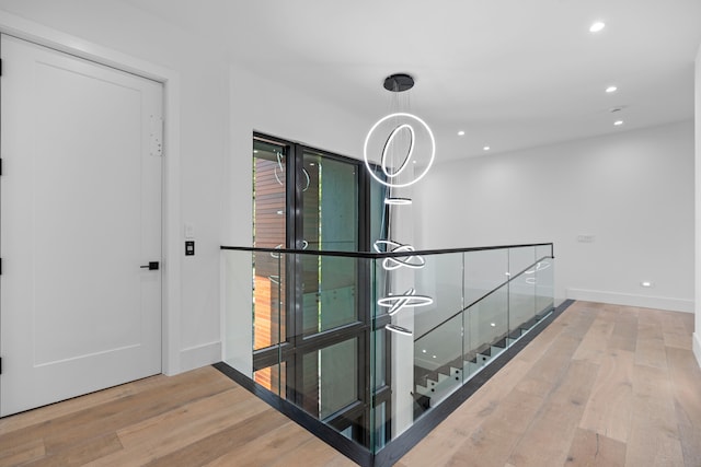 hall featuring hardwood / wood-style floors and an inviting chandelier