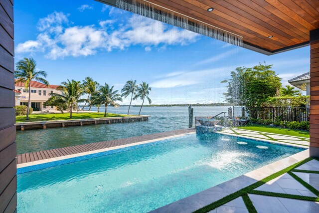 view of swimming pool featuring pool water feature, a lawn, and a water view