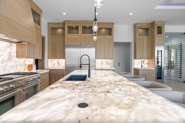 kitchen featuring sink, decorative backsplash, hanging light fixtures, custom range hood, and premium appliances