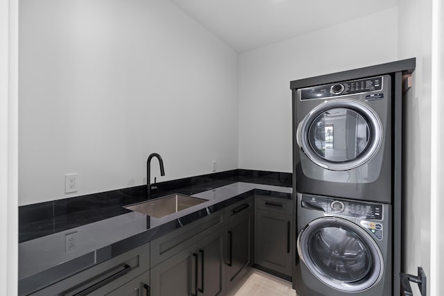 clothes washing area with cabinets, stacked washer / drying machine, and sink