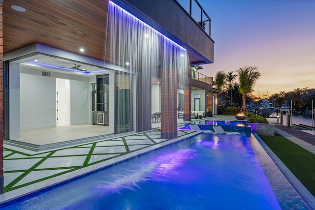 pool at dusk with a patio area