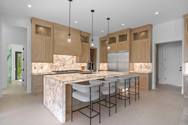 kitchen with decorative light fixtures, backsplash, stainless steel appliances, and a center island with sink