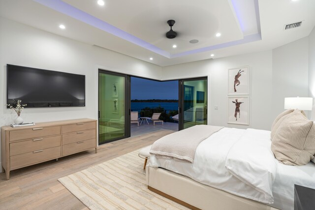 bedroom with a raised ceiling, access to outside, ceiling fan, and light hardwood / wood-style floors