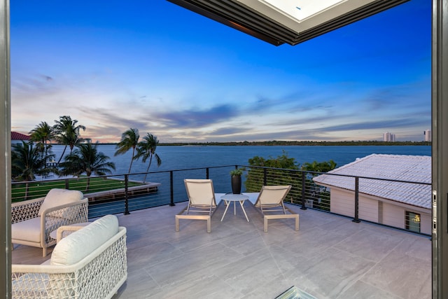 patio terrace at dusk with a balcony and a water view