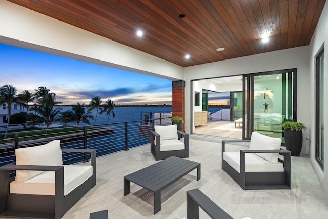 patio terrace at dusk featuring a balcony, an outdoor living space, and a water view