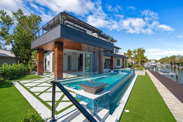 rear view of property with a lawn, pool water feature, a water view, a patio, and a balcony