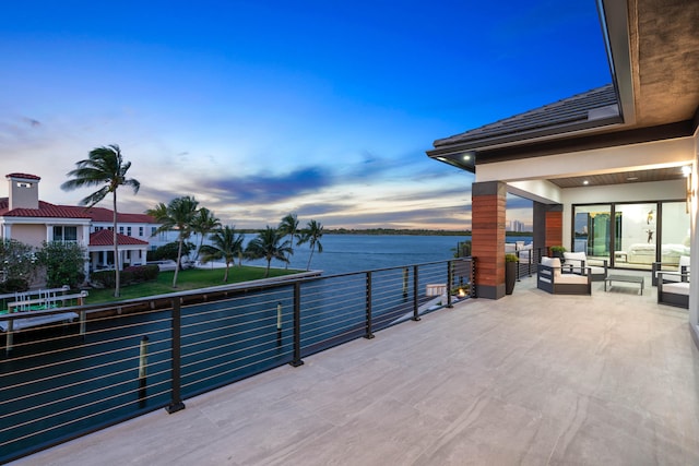 deck at dusk with a water view and an outdoor living space