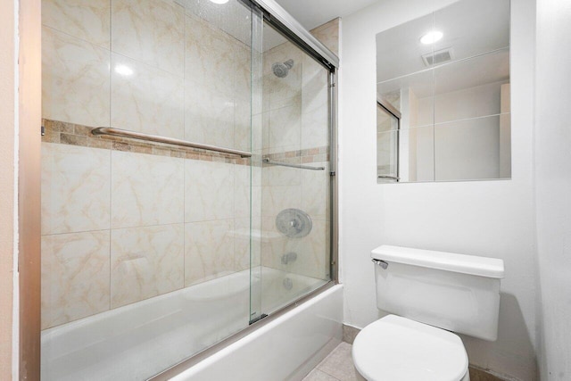 bathroom featuring toilet, tile patterned floors, and bath / shower combo with glass door