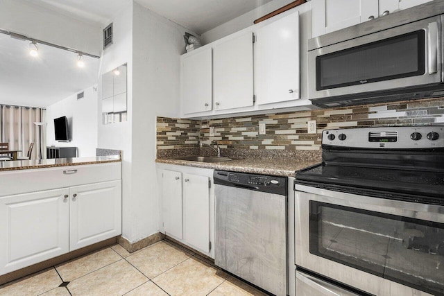 kitchen with decorative backsplash, white cabinets, light tile patterned floors, appliances with stainless steel finishes, and sink