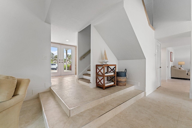 interior space featuring lofted ceiling, french doors, and a textured ceiling