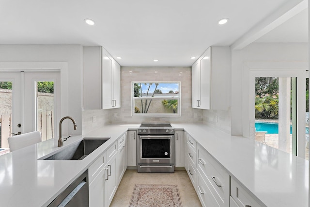 kitchen with white cabinets, stainless steel appliances, tasteful backsplash, and sink