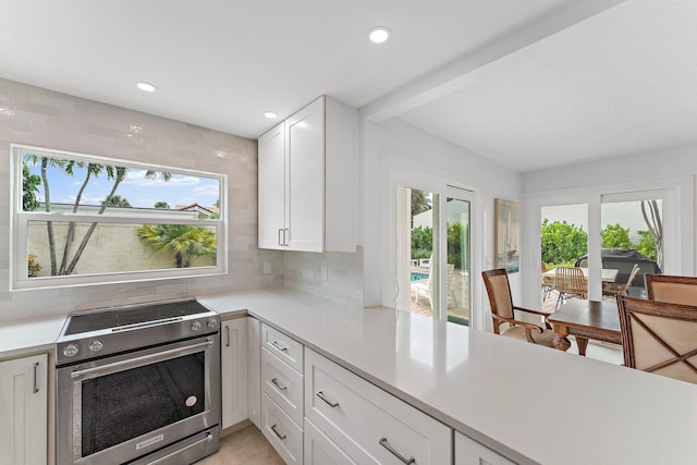 kitchen featuring white cabinetry, a wealth of natural light, and electric range