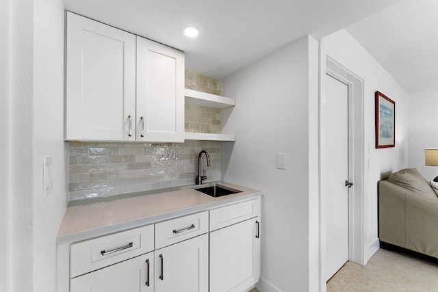 bar with white cabinets, light tile patterned floors, tasteful backsplash, and sink