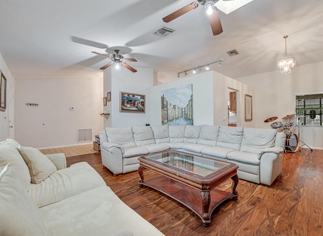 living room with rail lighting, vaulted ceiling, hardwood / wood-style floors, and ceiling fan with notable chandelier