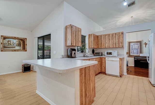 kitchen featuring light wood-type flooring, white appliances, kitchen peninsula, sink, and vaulted ceiling