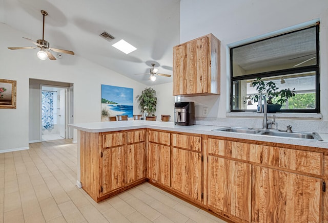 kitchen with ceiling fan, sink, kitchen peninsula, and vaulted ceiling